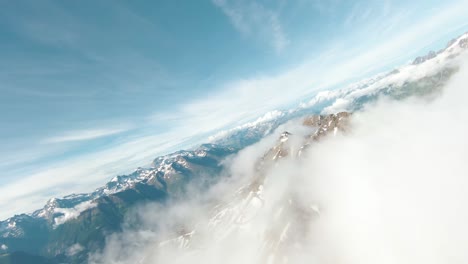 aerial drone flight over icy mountains and above clouds with fpv drone turning around in switzerland on sunny summer day with spectacular panorama