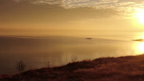 Aerial-dolly-to-solo-fisherman-on-mirror-like-waters,-perfect-reflection-of-sky