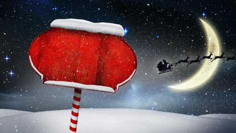 snow falling over red wooden sign post on winter landscape against moon in the night sky