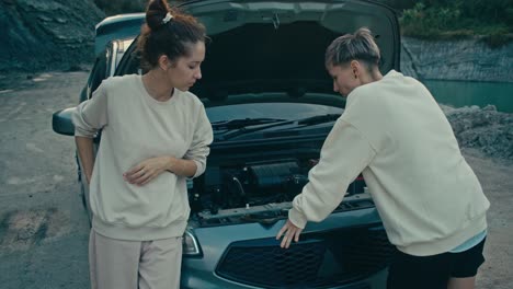 women trying to fix a broken car