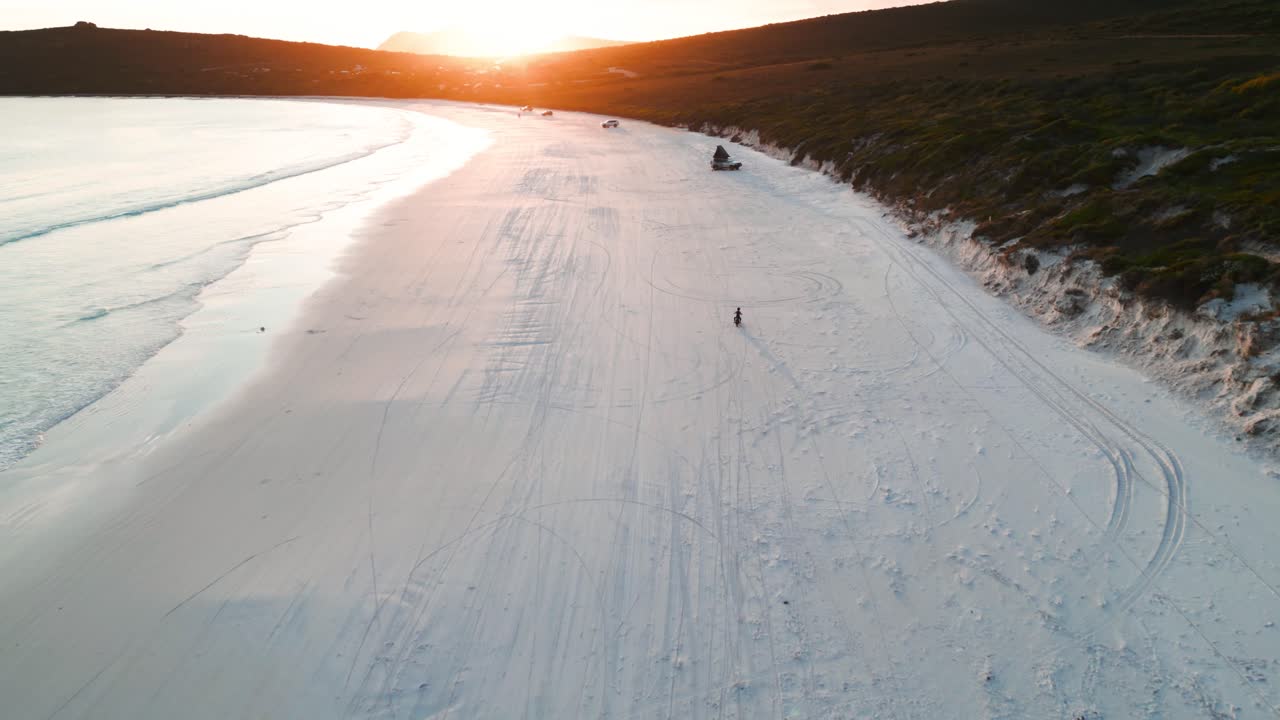 imagen reveladora de una motocicleta conduciendo en la bahía de la suerte en el parque nacional de cape legrand al atardecer, australia occidental