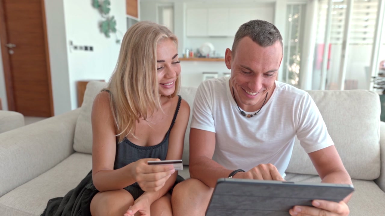 Giovane coppia che fa shopping online con tablet e carta di credito sul divano