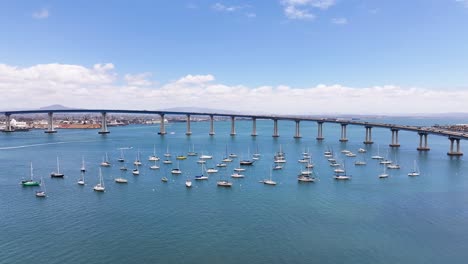 aerial pan around mooring sailboats next to coronado bridge in san diego bay