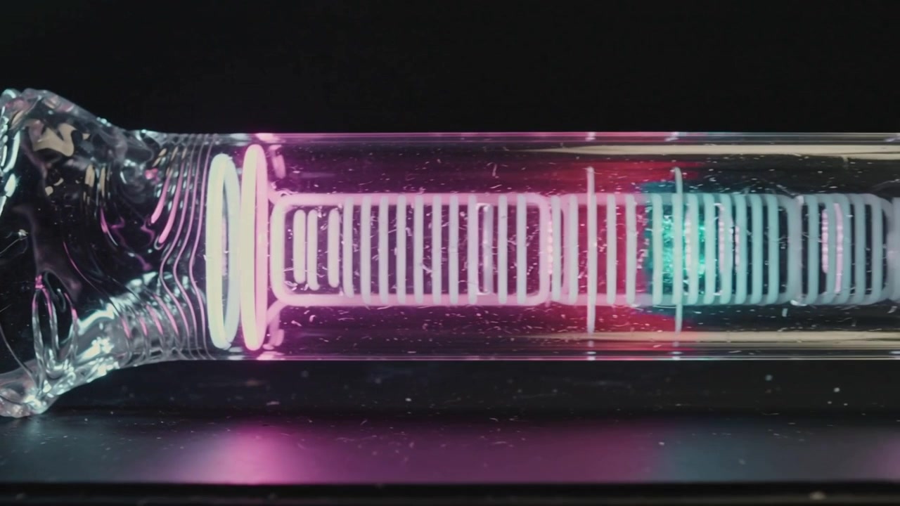 Magenta glow causing ladder array lighting and extending along glass tube with blown neck, tabletop