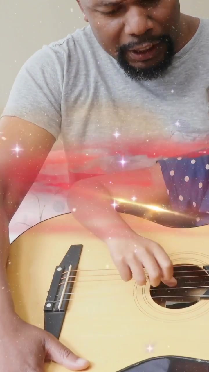 Video verticale: Bambino che strimpella la chitarra, un adulto che gli guida la mano e canta, creando un caldo legame musicale.