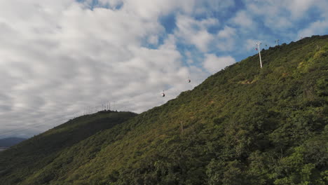 Drohnenschwenk-Von-Seilbahnen-Oder-Gondeln-Auf-Grünen-Hügeln,-En-Salta,-Argentinien-Mit-Dramatischen-Wolken