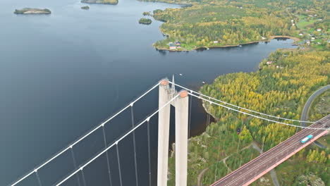Aerial-View-Of-Concrete-Pylon-Of-The-Suspension-Bridge-Of-Hogakustenbron-Above-Colorful-Trees-In-Sweden