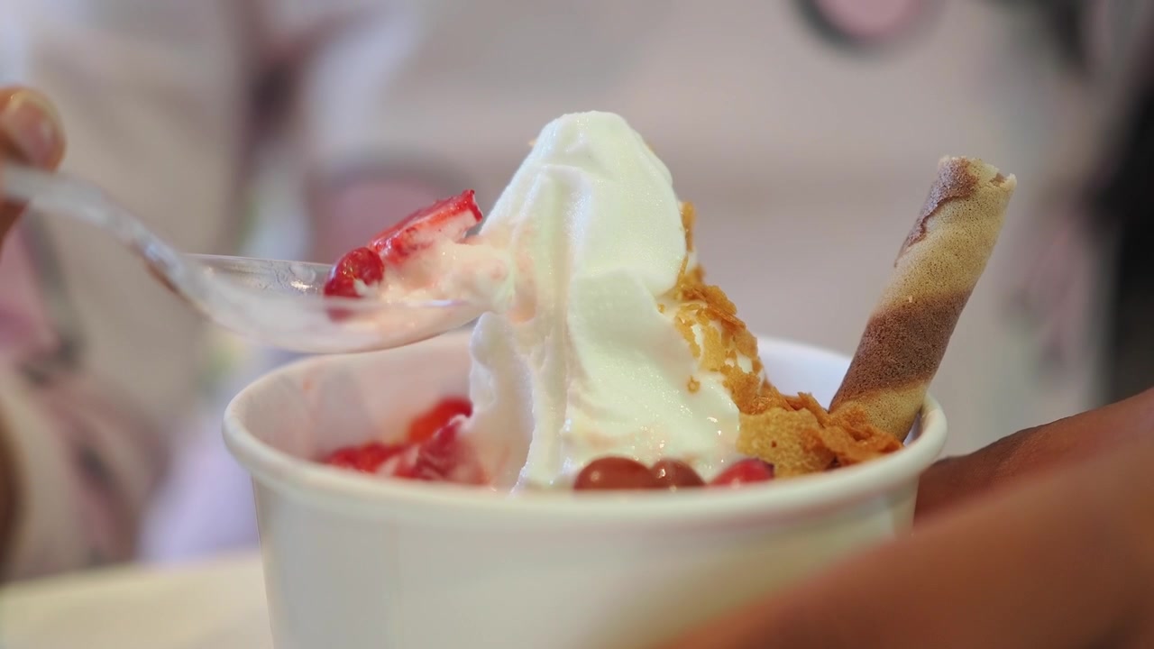 Persona che mangia gelato soft con guarnizioni