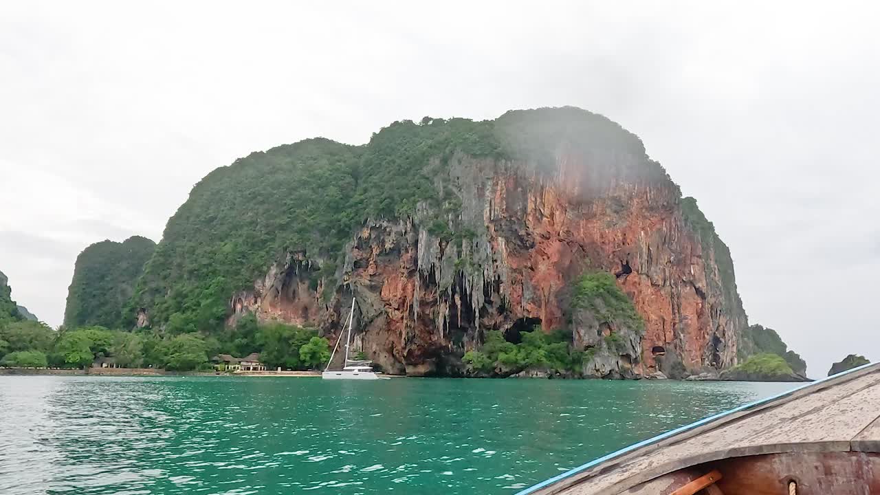 보트 가 울창 한 절벽 이 있는 경치 좋은 섬 에 접근 하고 있다