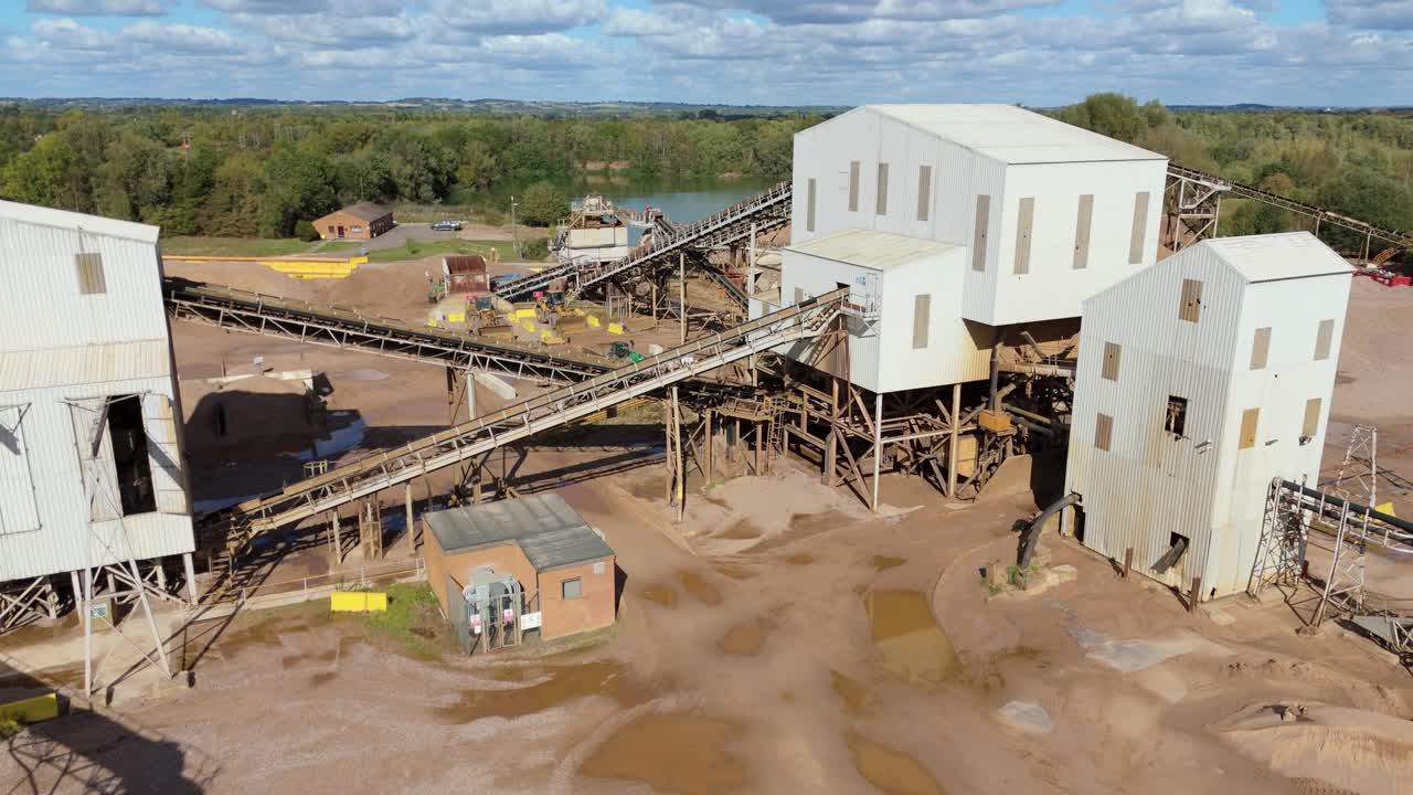 Drone flyover of open quarry near Nottingham, UK, with gravel piles, asphalt processing, and industrial machinery