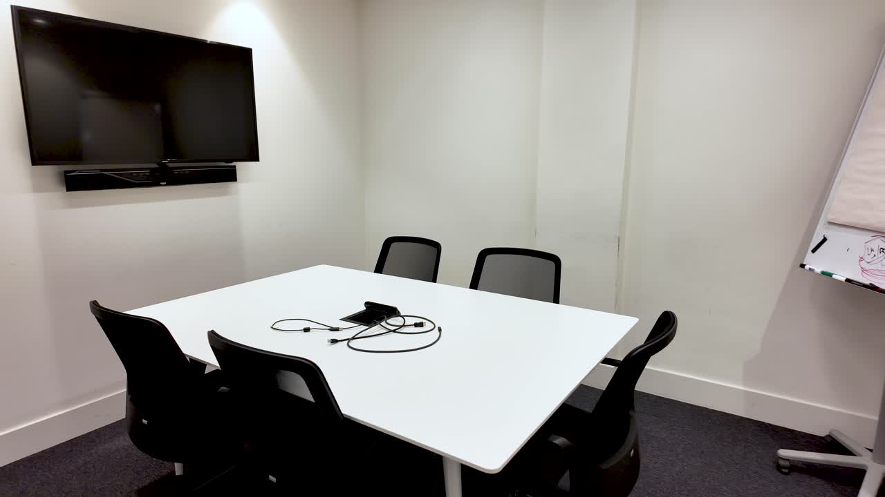 Interior de sala de reuniones moderna con mesa blanca, sillas negras, pantalla de televisión y rotafolio para presentaciones corporativas y reuniones de negocios. Espacio de oficina
