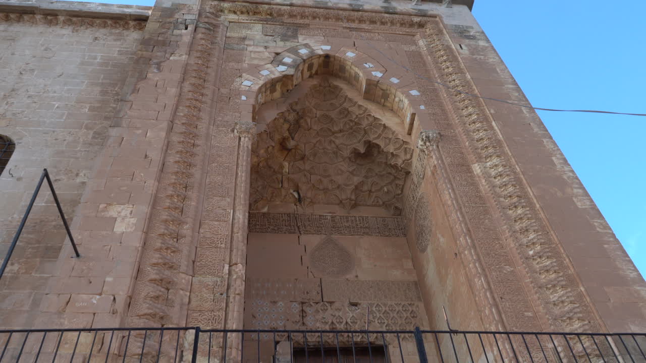 vemos la puerta principal de la madraza zinciriye, hecha con un magnífico trabajo en piedra, desde el ángulo inferior hacia arriba, y la cámara se aleja para ver toda la puerta