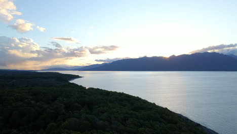 slow aerial slider view of vast blue lake surrounded by mountains and forest