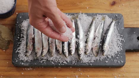seasoning anchovies on a cutting board