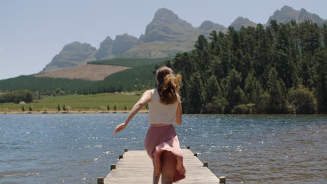 Mujer-Joven-Corriendo-Saltando-Del-Embarcadero-En-El-Lago-Chapoteando-En-El-Agua-Disfrutando-De-La-Libertad-De-Verano