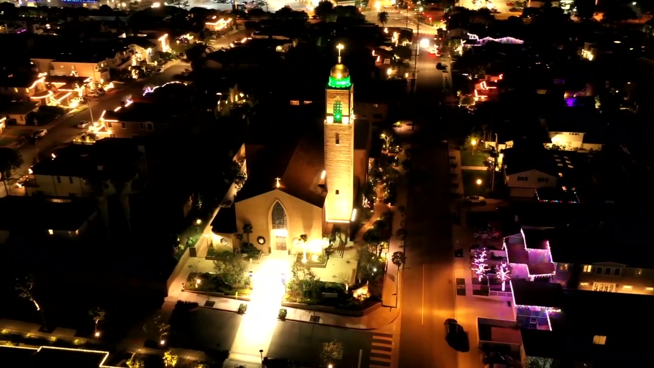 Vídeo aéreo de drone da Igreja American Martyrs em Manhattan Beach, CA, EUA. Luzes de Natal vermelhas e verdes iluminam a torre do sino desta impressionante igreja católica na Califórnia