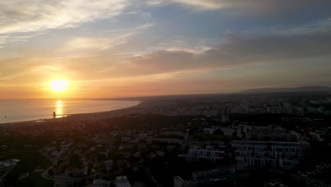 vista aérea de la puesta de sol con una atmósfera de hora dorada, los rayos del sol proyectando un cálido resplandor sobre las nubes y el área residencial de una ciudad costera