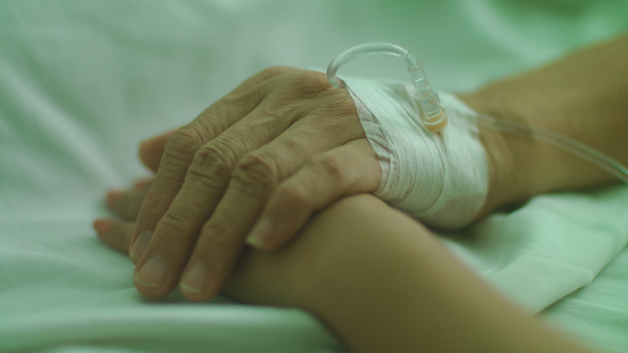 Primo piano di un paziente anziano e malato che tiene per mano una donna