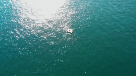 órbita-Aérea-Sobre-Plataforma-Flotante-En-El-Mar-Esmeralda-Con-Reflejos-Solares,-Océano-Pacífico