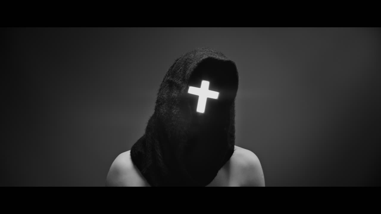 Masked and hooded man with cross of light glowing on his face rise his head