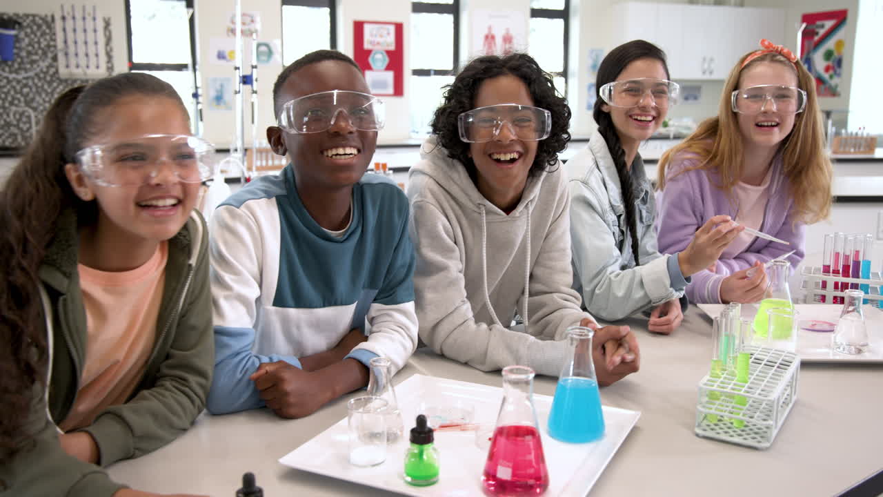 In school, kids wearing safety goggles experimenting with colorful liquids in science class