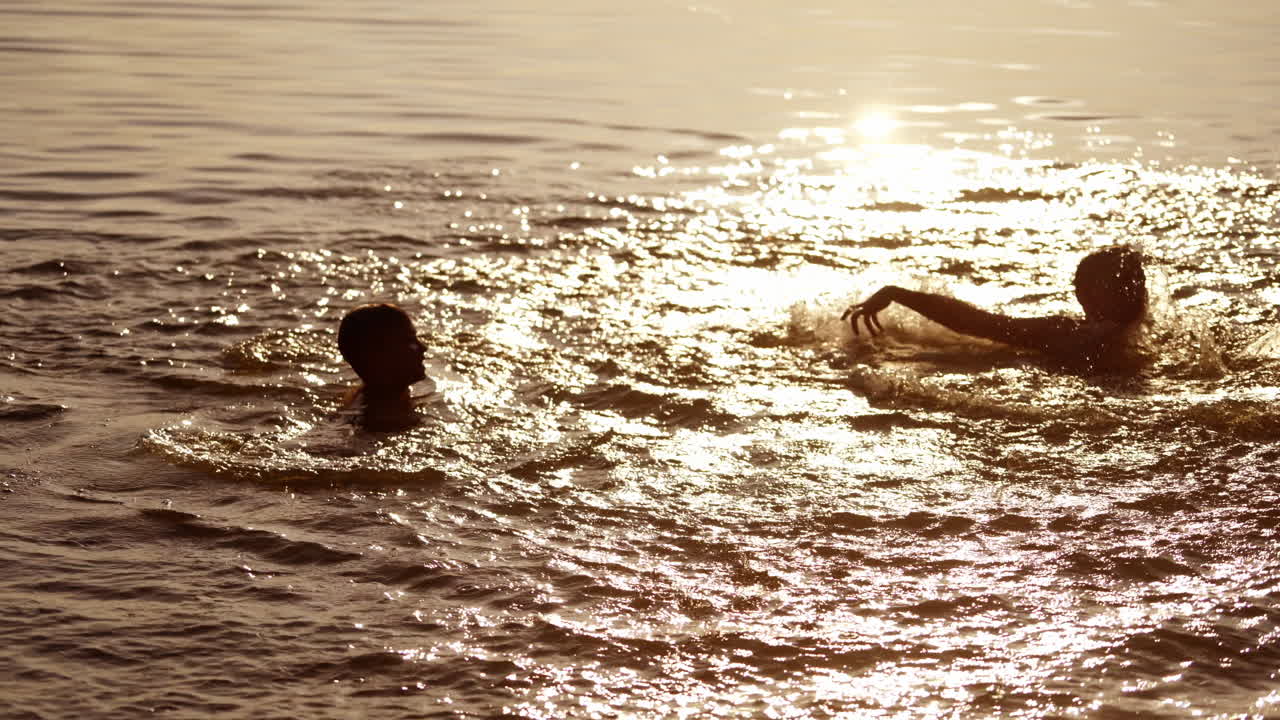 Joyful children playing with water at sunset. Young boys having fun in the river. Two brothers splashing in water in the evening.