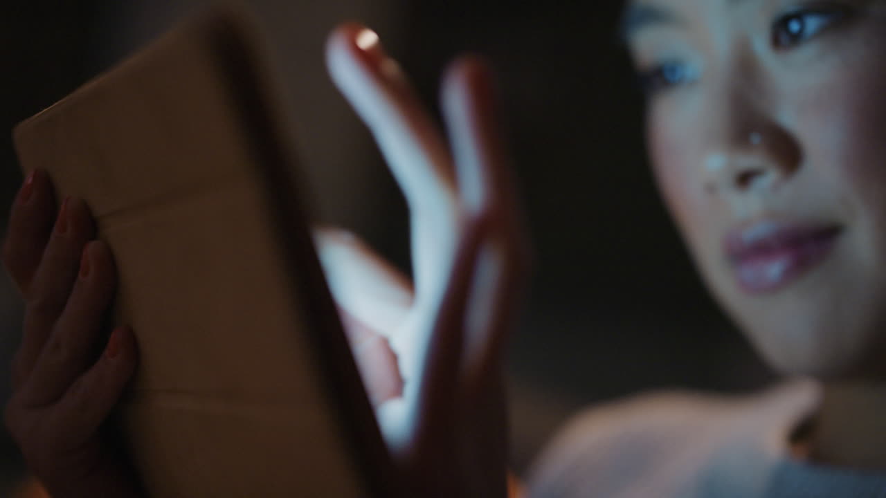 hermosa mujer asiática usando tecnología de tableta digital en casa tarde en la noche