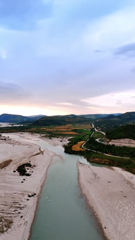 picturesque landscape of albania from top view. drone footage over the narrow river with sandy banks. rare cars go by the highways in the mountains. vertical video.