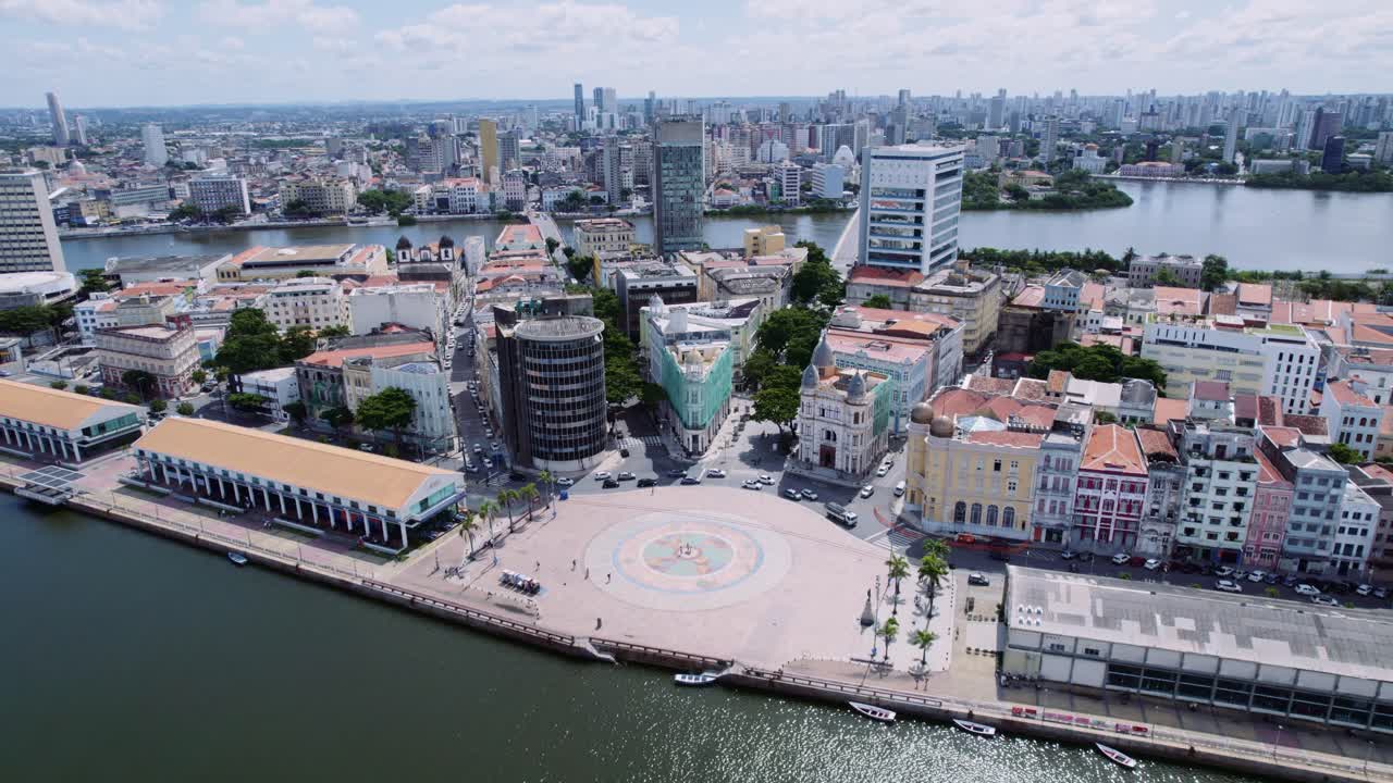 Aerial view of a vibrant waterfront city with a large public square and diverse architecture