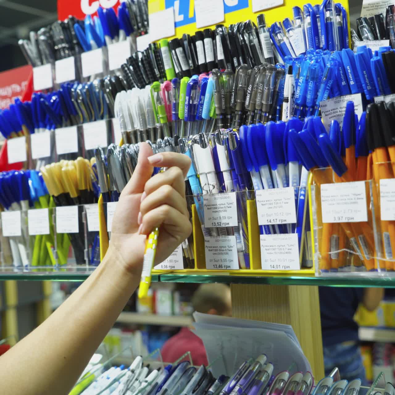 Vinnitsa, Ukraine - August 20, 2018: Purchase of stationery in the store. Woman's hand chooses a pens.