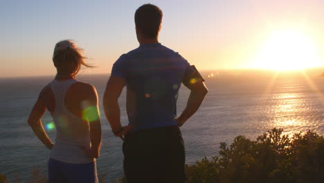 hombre y mujer admirando una vista costera después de correr