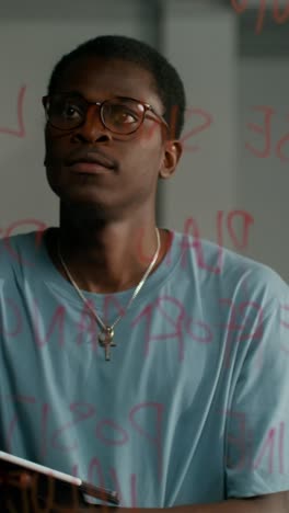 man looking at a glass board with writing on it