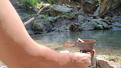 person add wood to hobo cooker to cook soup in nature