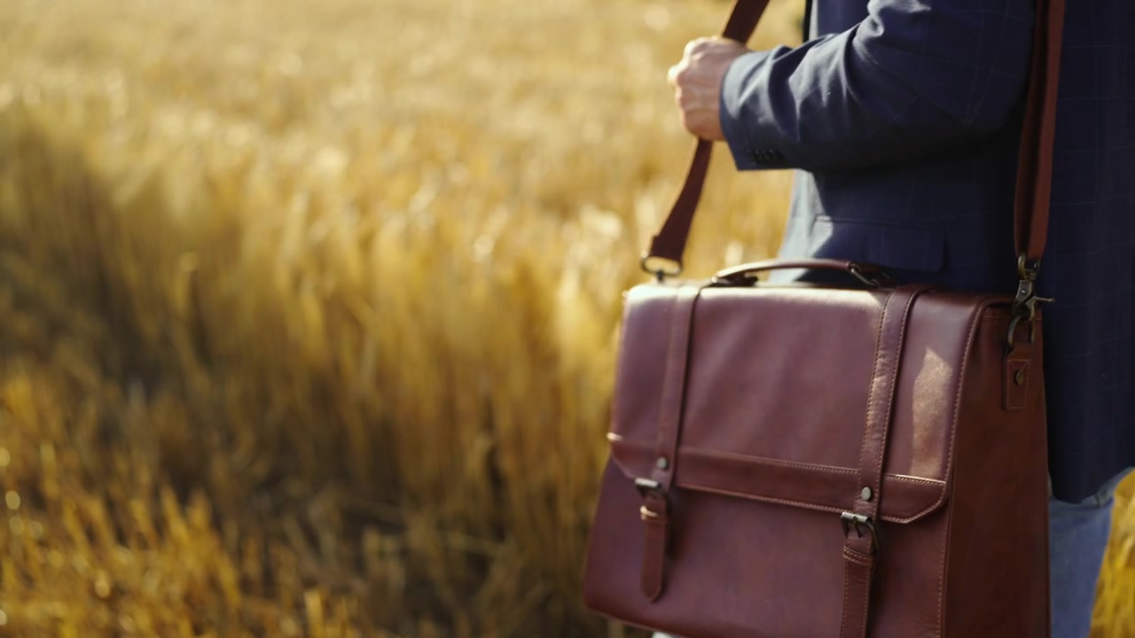 Uomo d'affari che cammina attraverso un campo di grano dorato