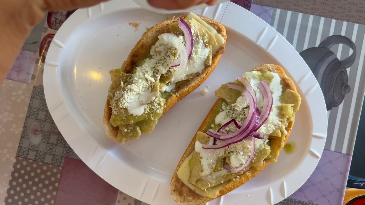 Chilaquiles verdi serviti su pane, guarniti con panna e cipolla per colazione