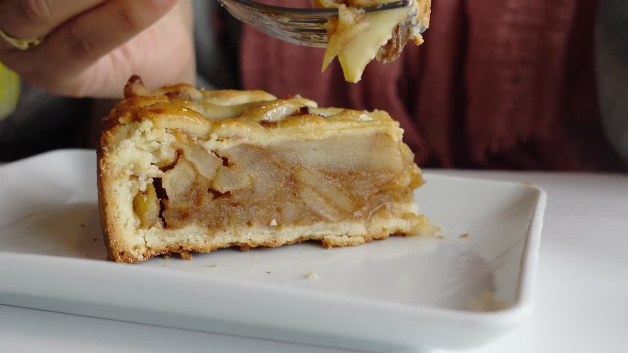 cerca de una persona comiendo una rebanada de pastel de manzana con un tenedor