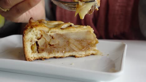 close up of a person eating a slice of apple pie with a fork