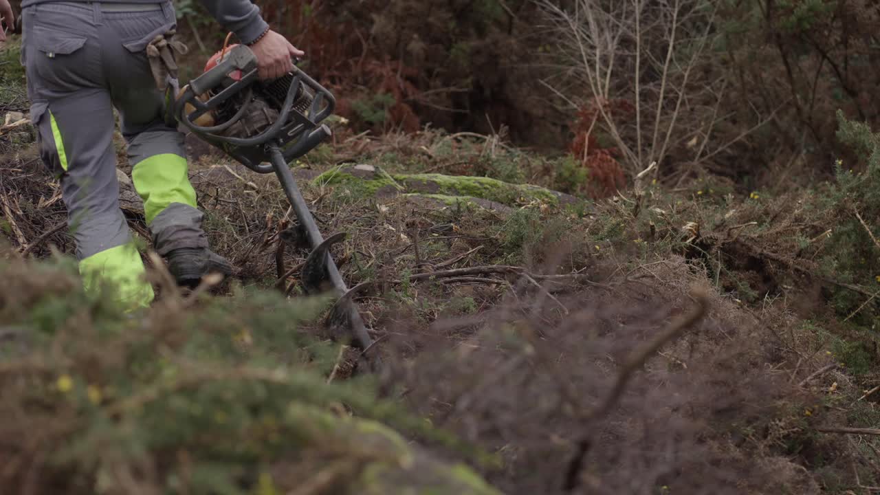 Forestry worker uses earth auger to prepare soil for tree planting