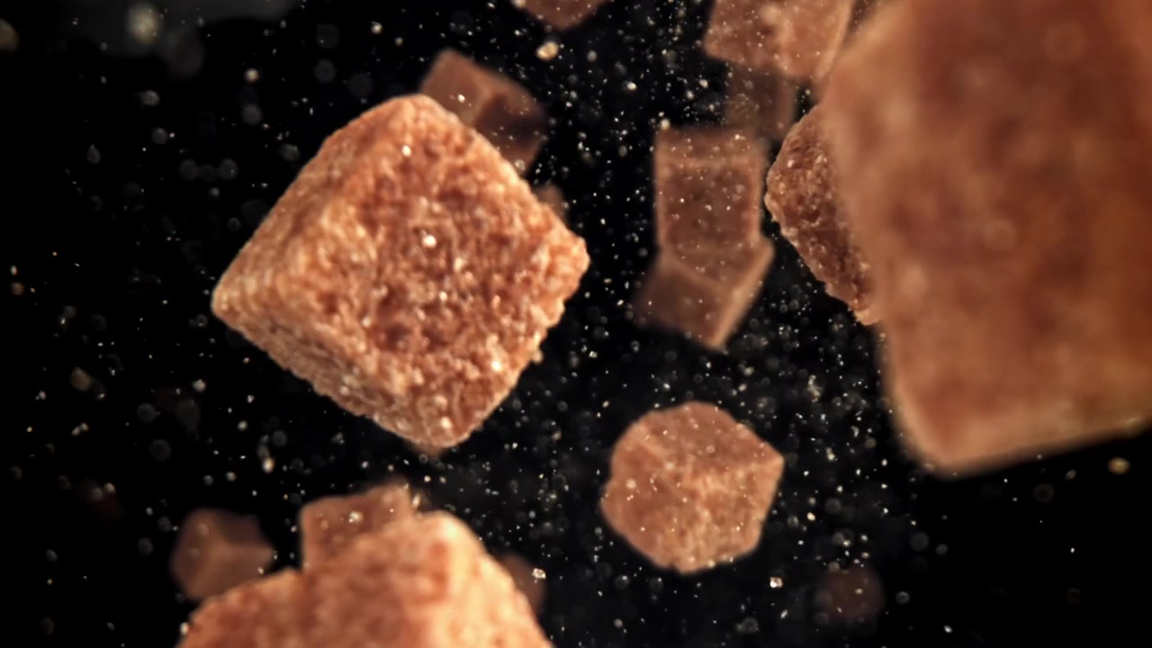 Brown Sugar Cubes Falling in Slow Motion on Black Background