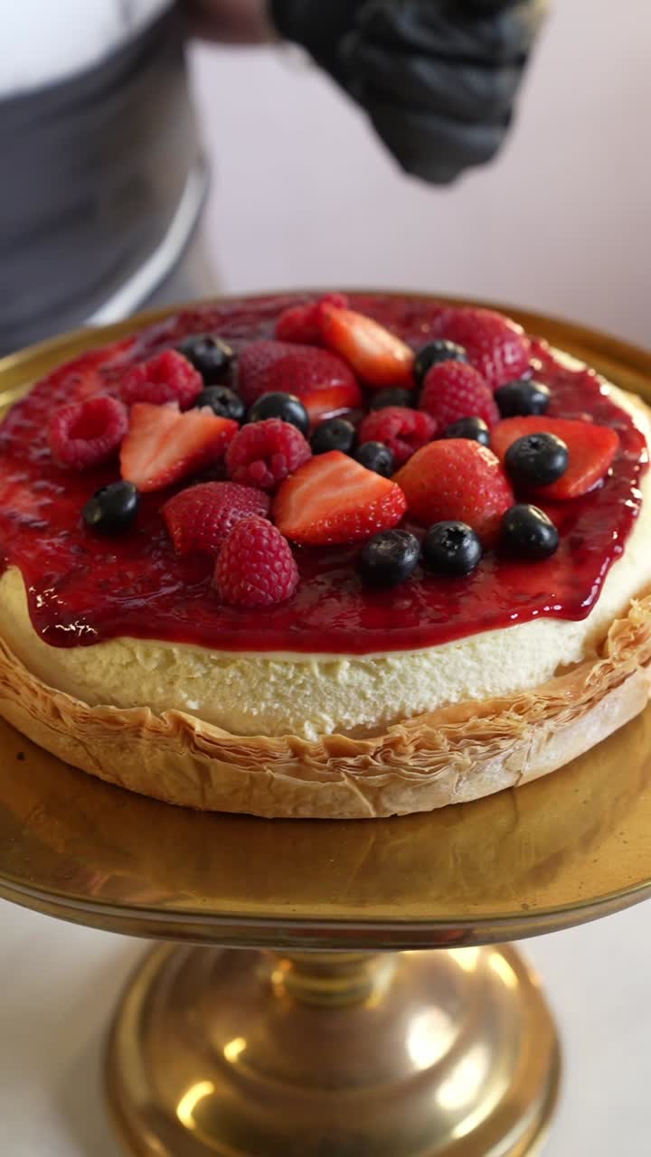 A chief puts blueberry on a Strawberry jam cake in a restaurant, close up shot, insert shot