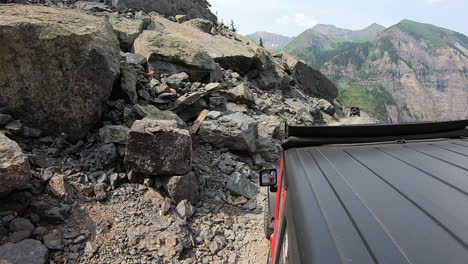 rooftop of 4wd vehicle following another on narrow trail cut in mountain side high above poughkeepsie gulch in colorado