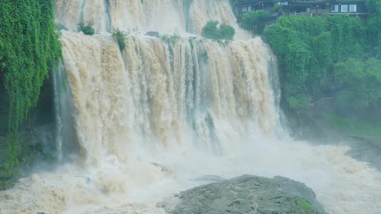 Cảnh quay tĩnh cận trung tập trung vào chân thác Phù Dung hùng vĩ đổ xuống những tảng đá bên dưới.