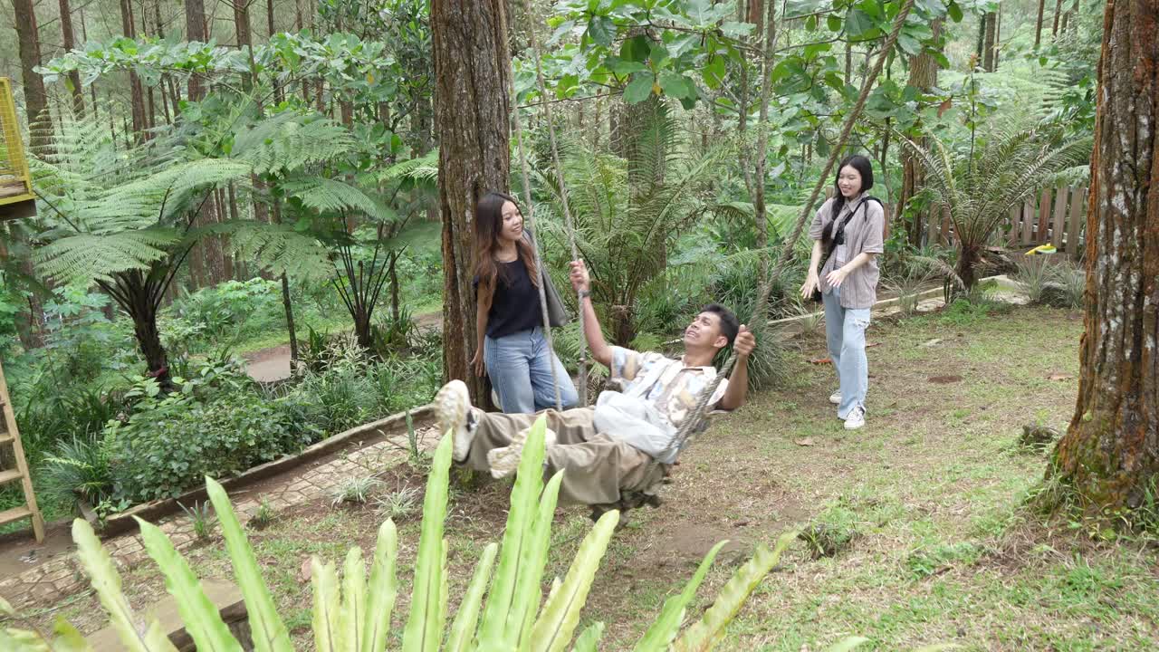 Indonesian Friends Playing on a Swing in Forest During Outdoor Travel Adventure