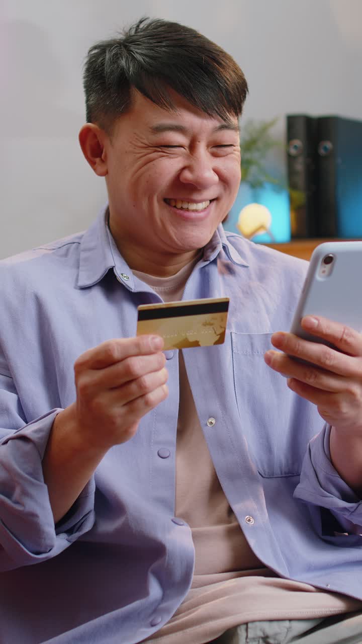 Pria dewasa Asia menggunakan kartu kredit bank dan ponsel pintar untuk transfer uang saat berbelanja online