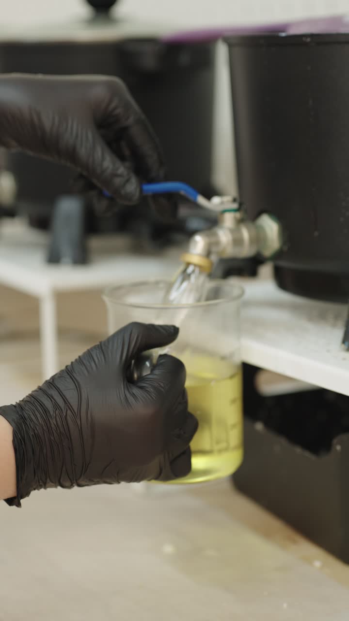 Pouring liquid into beaker with gloved hands