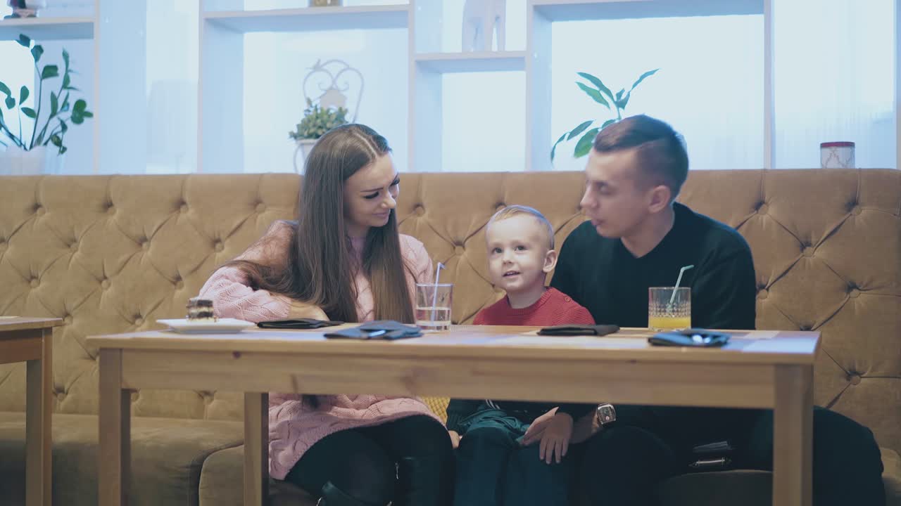 adorable niño en suéter rojo besa a su padre y su madre