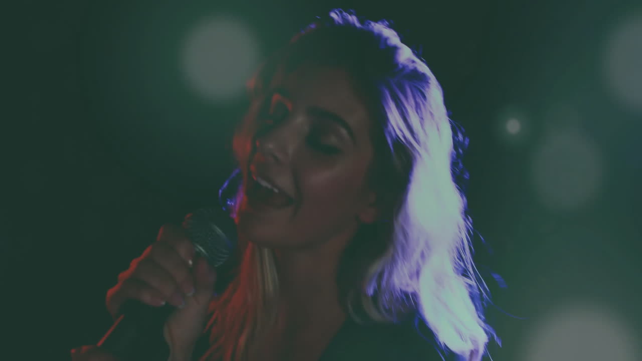 Woman singing on stage, audio technology graphs floating over microphone and colored lights
