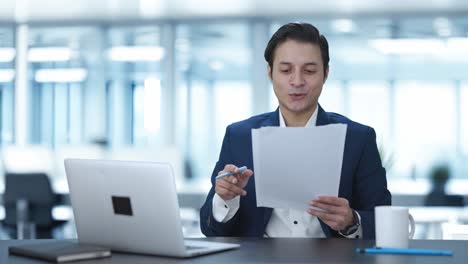 happy indian manager reading and signing reports