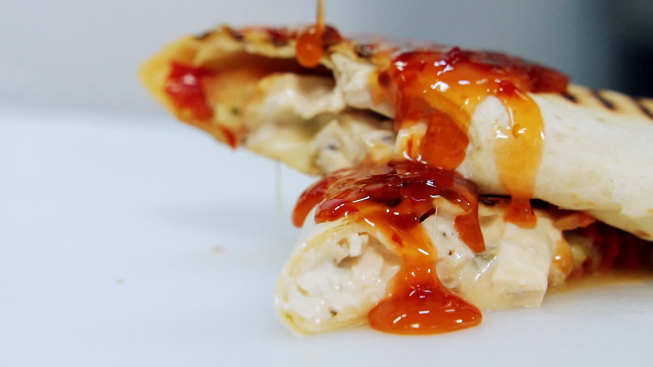 Ready grilled pita pouring with red sauce. Delicious cooked shawarma pouring by gravy. Beautiful presentation of food. Close-up