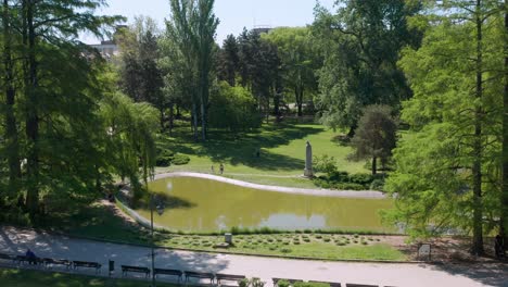 Aerial-shot-rising-up-and-circling-around-a-pond-in-Danube-Park-in-Novi-Sad,-Serbia